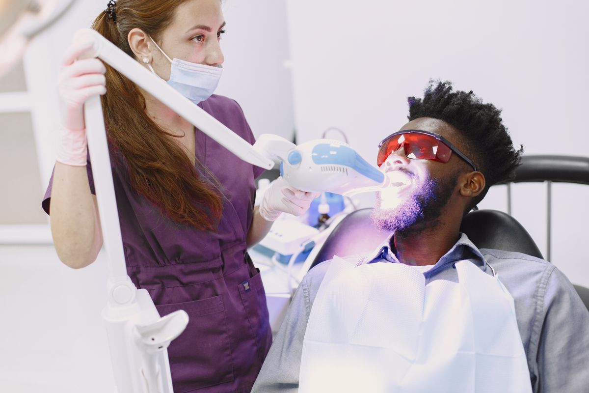 Dentist using a whitening light during an in-office teeth whitening treatment